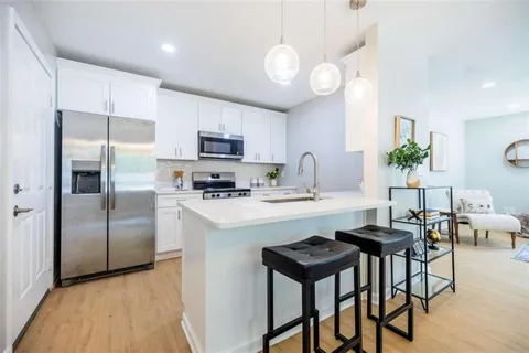 a kitchen with kitchen island granite countertop a sink cabinets and stainless steel appliances