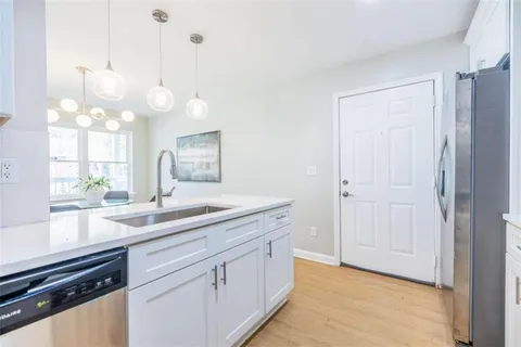 a kitchen with a sink and dishwasher with wooden floor