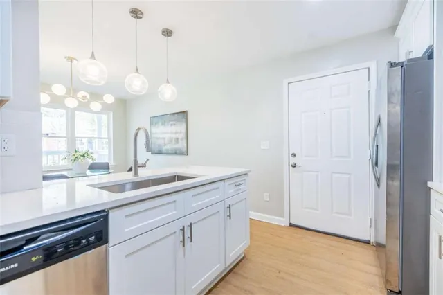 a kitchen with a sink and dishwasher with wooden floor