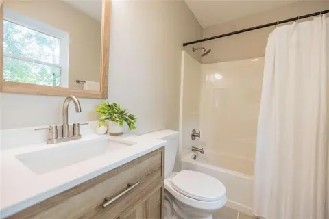 a bathroom with a sink a toilet a mirror and shower