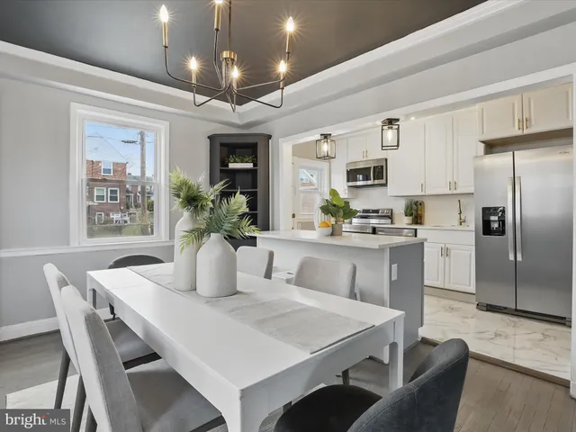 a kitchen with stainless steel appliances kitchen island granite countertop a dining table chairs and a refrigerator