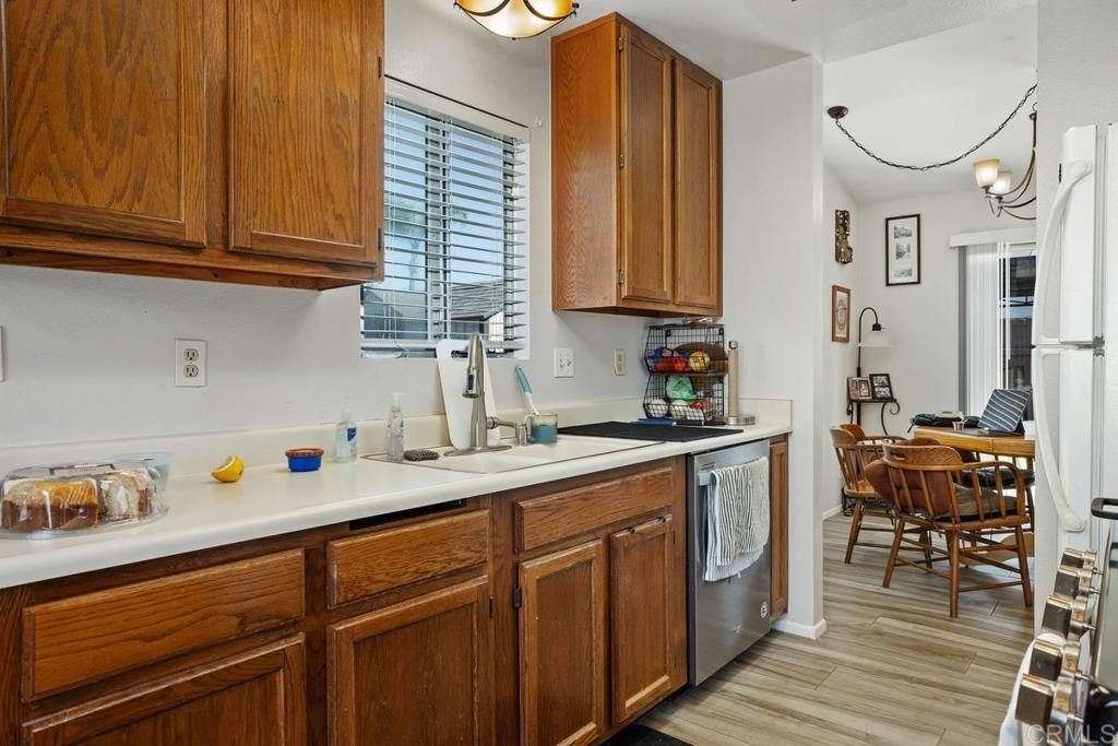4616 Arrowhead Court Oceanside, CA 92056 - Photo 21 of 50 a kitchen with stainless steel appliances granite countertop a sink dishwasher cabinets and dining table with wooden floor