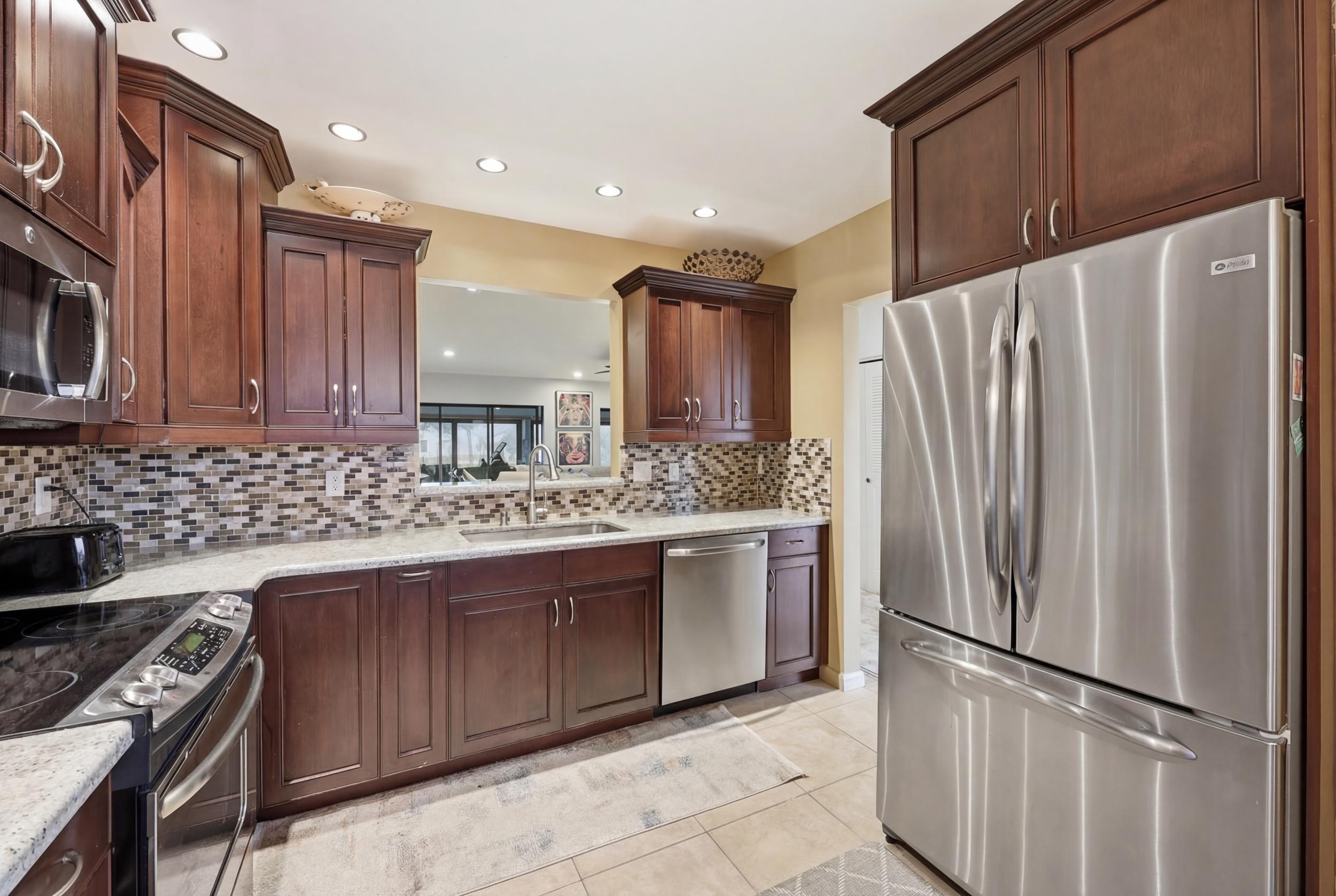 10768 Waterberry Drive Boca Raton, FL 33498 - Photo 8 of 26 a kitchen with stainless steel appliances granite countertop a refrigerator sink and stove