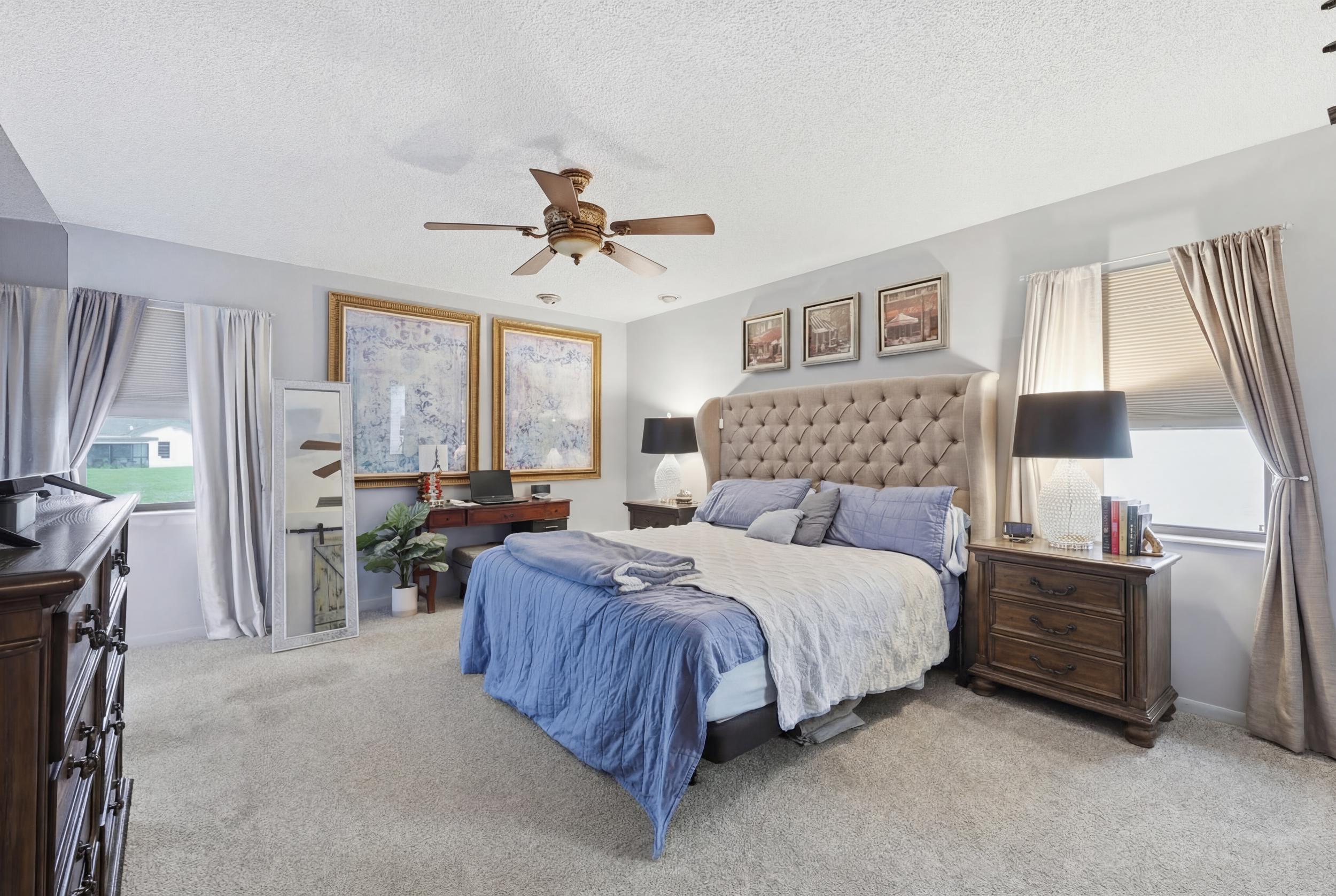 10768 Waterberry Drive Boca Raton, FL 33498 - Photo 9 of 26 a spacious bedroom with a bed a chandelier and a window