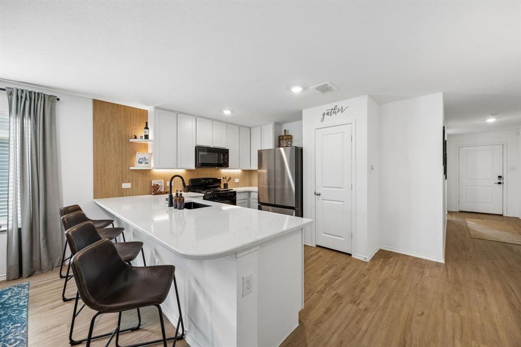 1025 Mountain Laurel Road Princeton, TX 75407 - Photo 5 of 30 a kitchen with stainless steel appliances a refrigerator a stove a sink dishwasher and a refrigerator with wooden floor