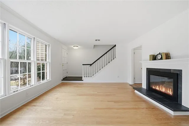 a view of an empty room with wooden floor fireplace and a window