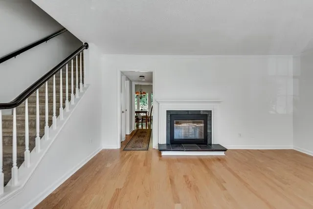 a view of an empty room with wooden floor fireplace and a window