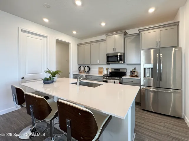a kitchen with kitchen island a stove a sink a microwave a refrigerator and white cabinets