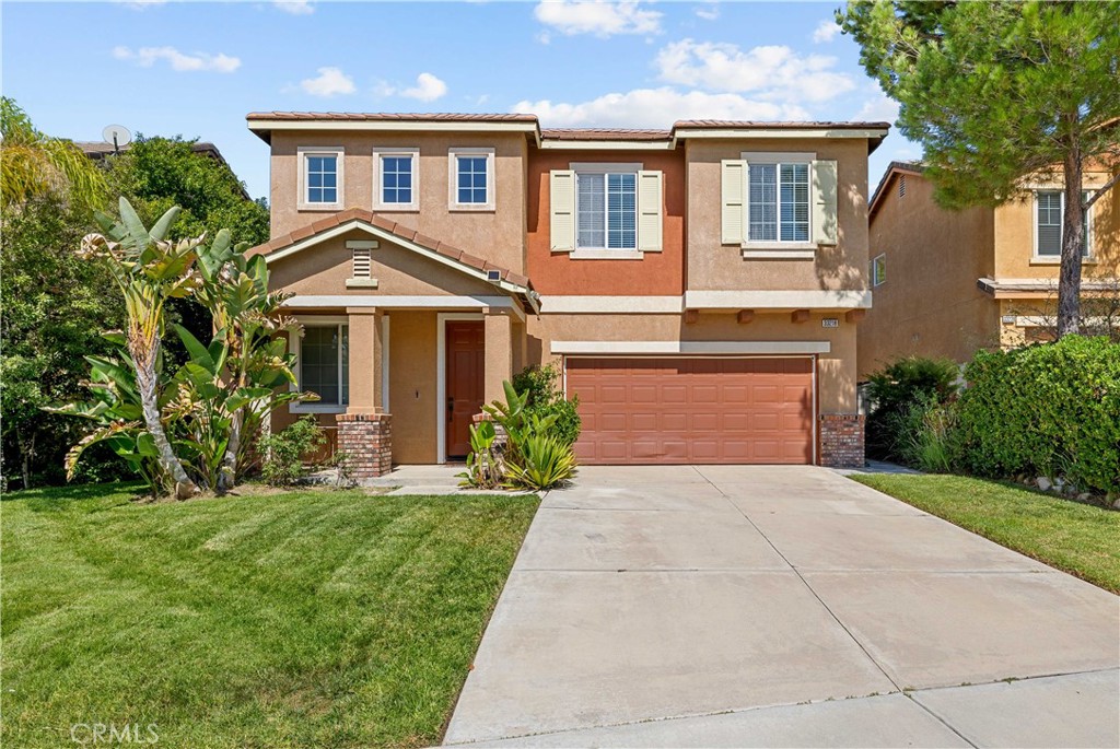a front view of a house with a yard and trees
