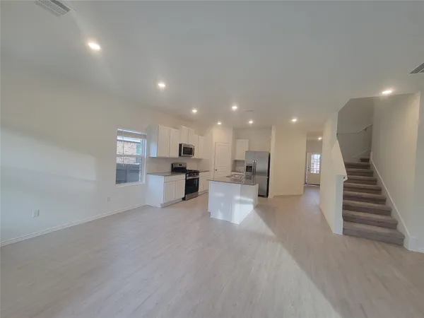a view of kitchen with kitchen island a sink wooden floor and a refrigerator
