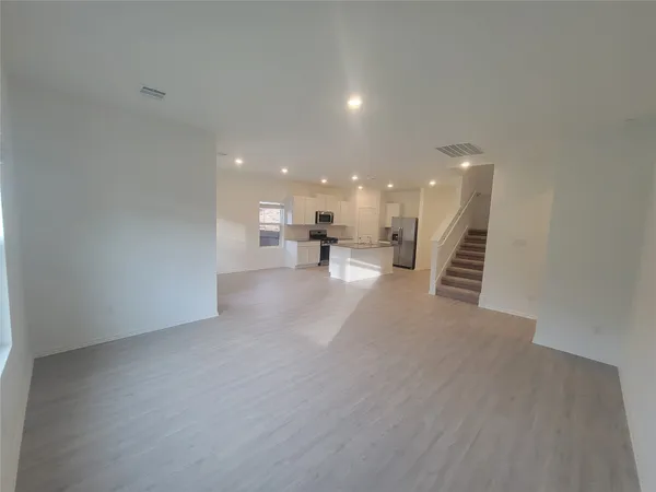 a view of a big room with wooden floor and a kitchen