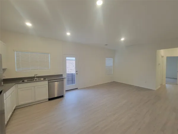 an empty room with kitchen stove sink and cabinets