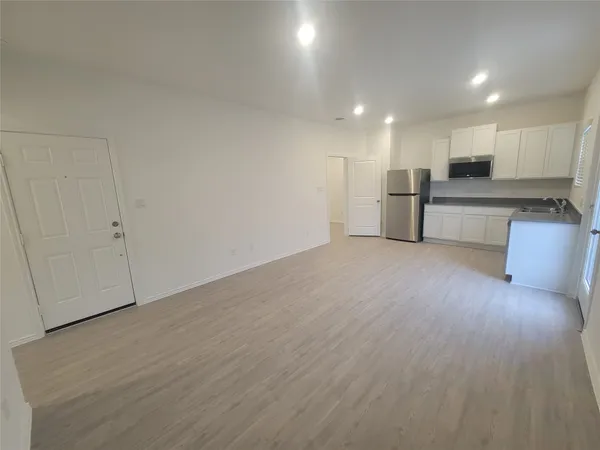 a view of kitchen with stainless steel appliances wooden floor and large window