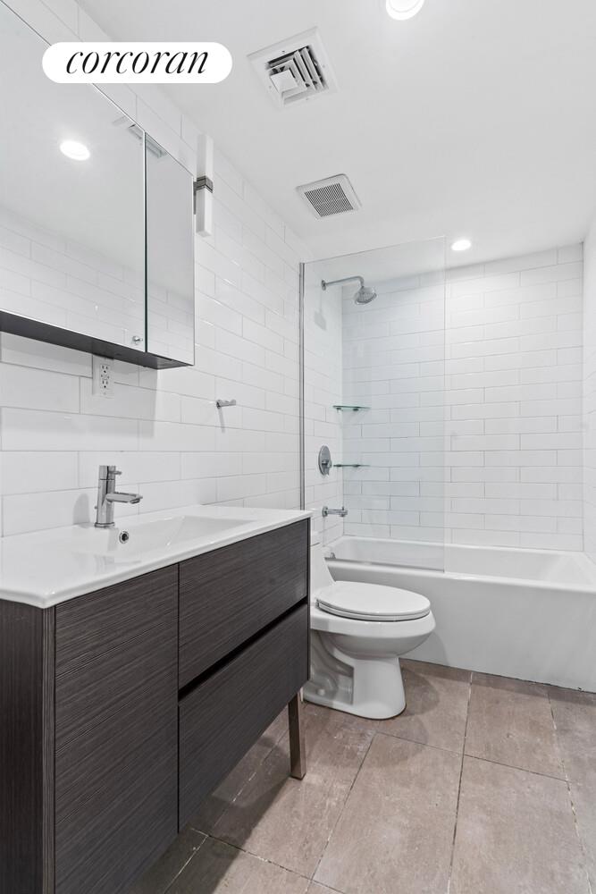 139 Rochester Avenue Brooklyn, NY 11213 - Photo 16 of 17 a bathroom with a toilet sink vanity tub and mirror