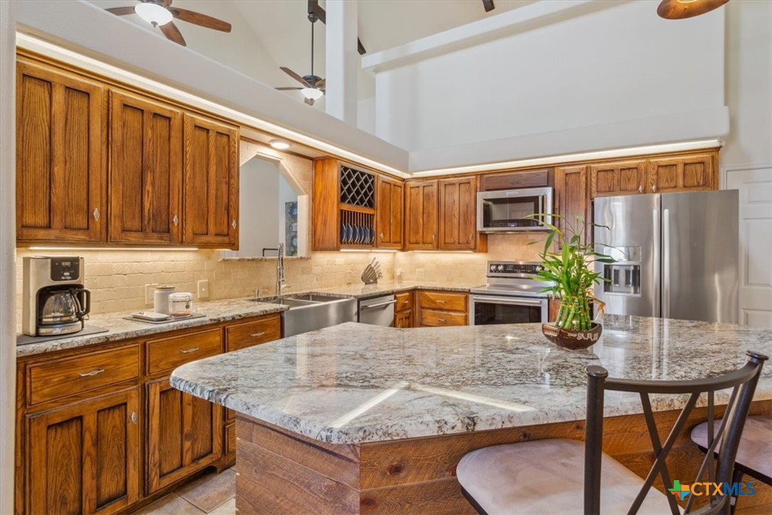 5306 Denmans Loop Belton, TX 76513 - Photo 7 of 46 a kitchen with stainless steel appliances granite countertop wooden cabinets a sink a stove a dining table and chairs
