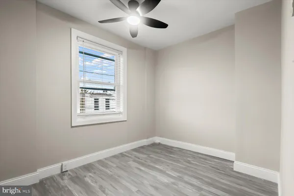 an empty room with wooden floor chandelier fan and windows
