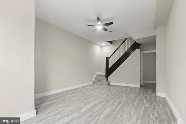 a view of an empty room with wooden floor and ceiling fan