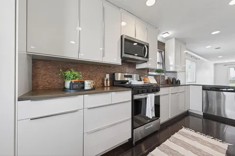 a kitchen with stainless steel appliances granite countertop white cabinets granite counter tops and a hard wood floors