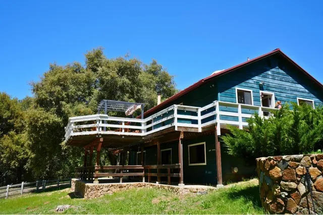 a view of a small house with wooden fence