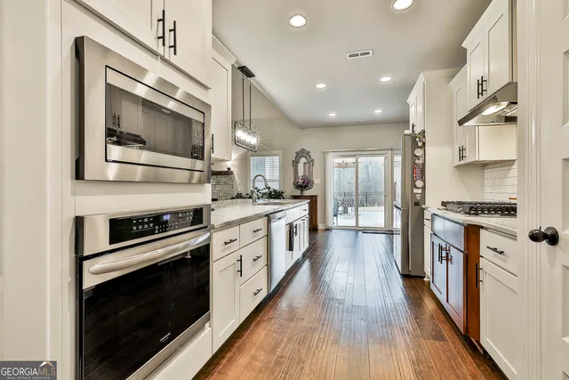 a large kitchen with stainless steel appliances granite countertop a lot of counter space and wooden floors