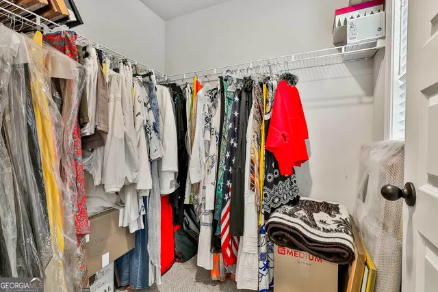 a view of walk in closet with clothes and shoes