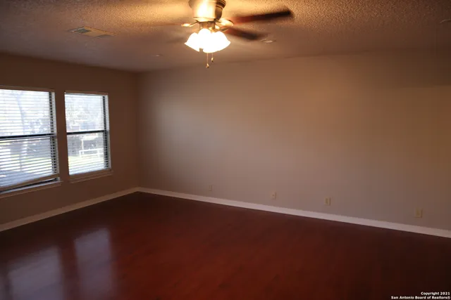 a view of an empty room with wooden floor and a window