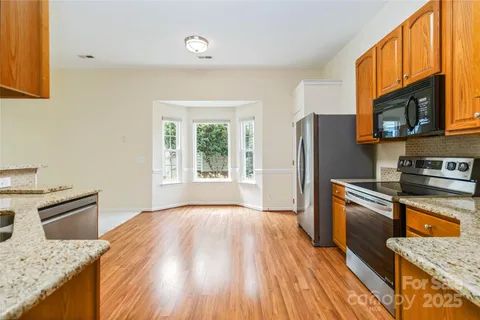 a kitchen with granite countertop a refrigerator stove top oven and sink