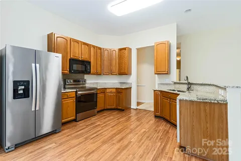 a kitchen with granite countertop wooden floors stainless steel appliances and a window