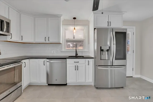 a kitchen with stainless steel appliances granite countertop a sink a stove and a refrigerator