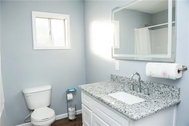 a bathroom with a granite countertop sink a toilet and a mirror