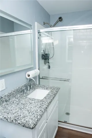 a bathroom with a granite countertop sink a mirror and shower