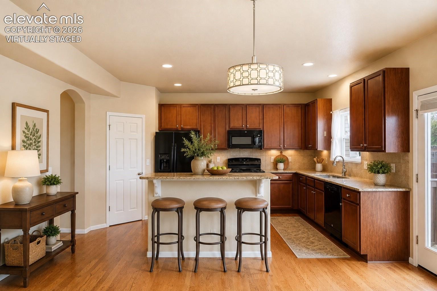 7274 Red Cardinal Loop Colorado Springs, CO 80908 - Photo 7 of 33 *Virtually Staged*
Kitchen featuring wood-finish flooring, wood cabinetry, stone countertops, and a built-in breakfast bar