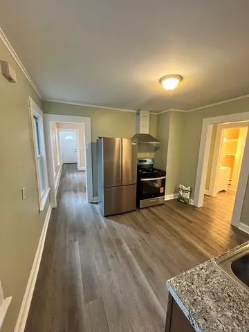 a kitchen with stainless steel appliances granite countertop a refrigerator a stove and a wooden floors