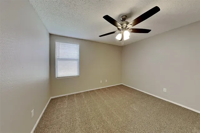 an empty room with ceiling fan and window