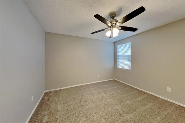 an empty room with a ceiling fan and a window