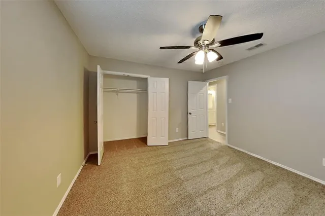 an empty room with chandelier fan and closet area