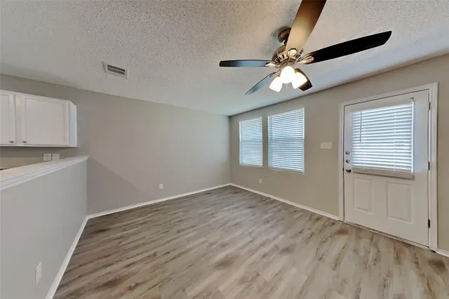 a view of an empty room with window and wooden floor