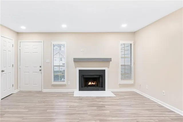 a view of an empty room with wooden floor fireplace and a window