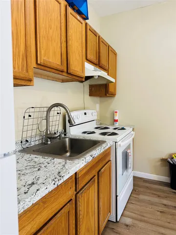 a kitchen with granite countertop a sink a stove and cabinets