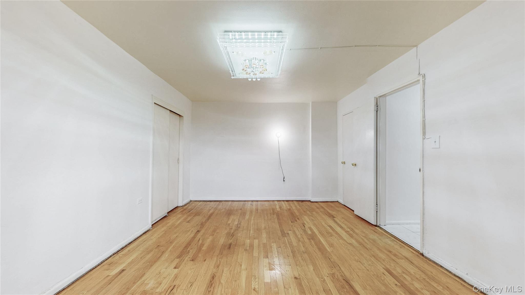 99-35 59th Avenue, Unit 4E Queens, NY 11368 - Photo 16 of 22 Empty room featuring light wood-style floors and baseboards