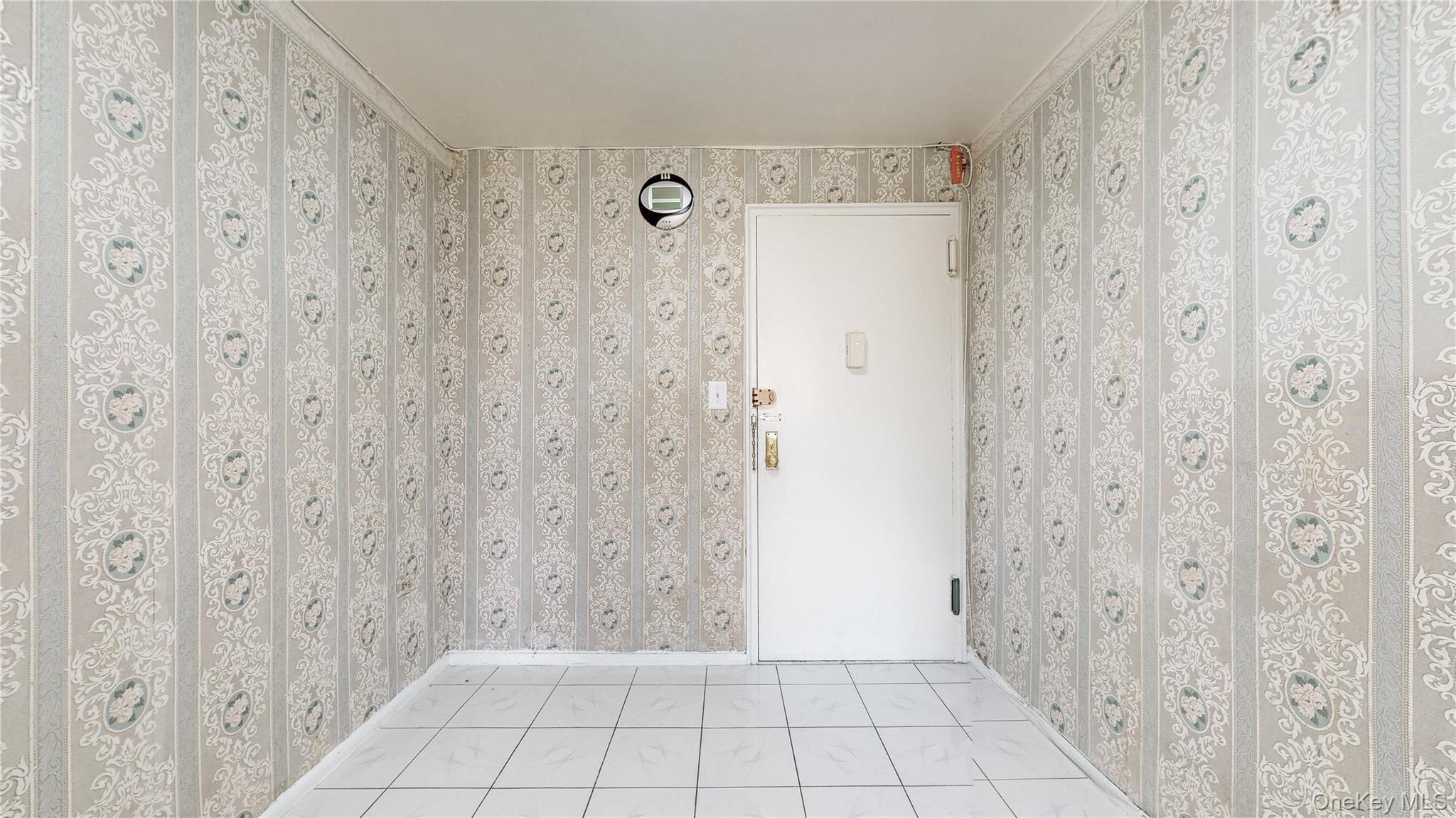 99-35 59th Avenue, Unit 4E Queens, NY 11368 - Photo 4 of 22 Empty room featuring light tile patterned flooring and wallpapered walls