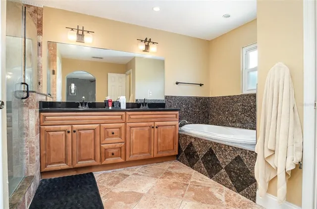 a bathroom with a granite countertop sink a mirror a shower and a bathtub