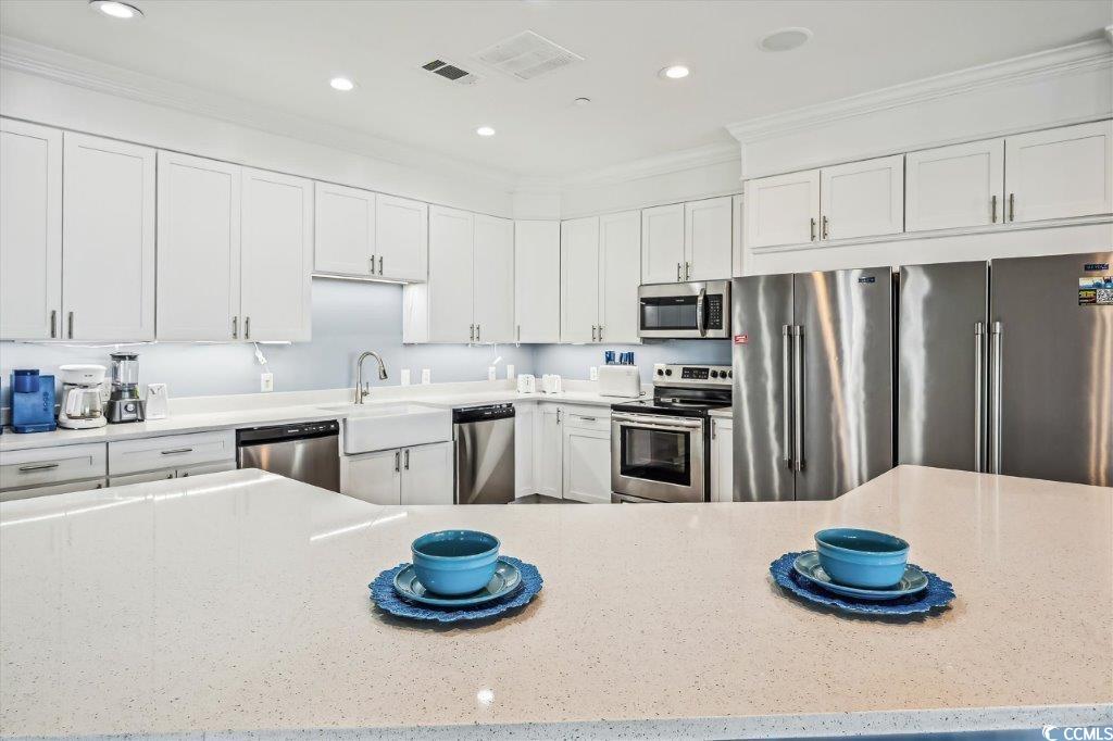 931 South Ocean Boulevard North Myrtle Beach, SC 29582 - Photo 10 of 40 Kitchen featuring stainless steel appliances, crown molding, white cabinets, light stone counters, and recessed lighting