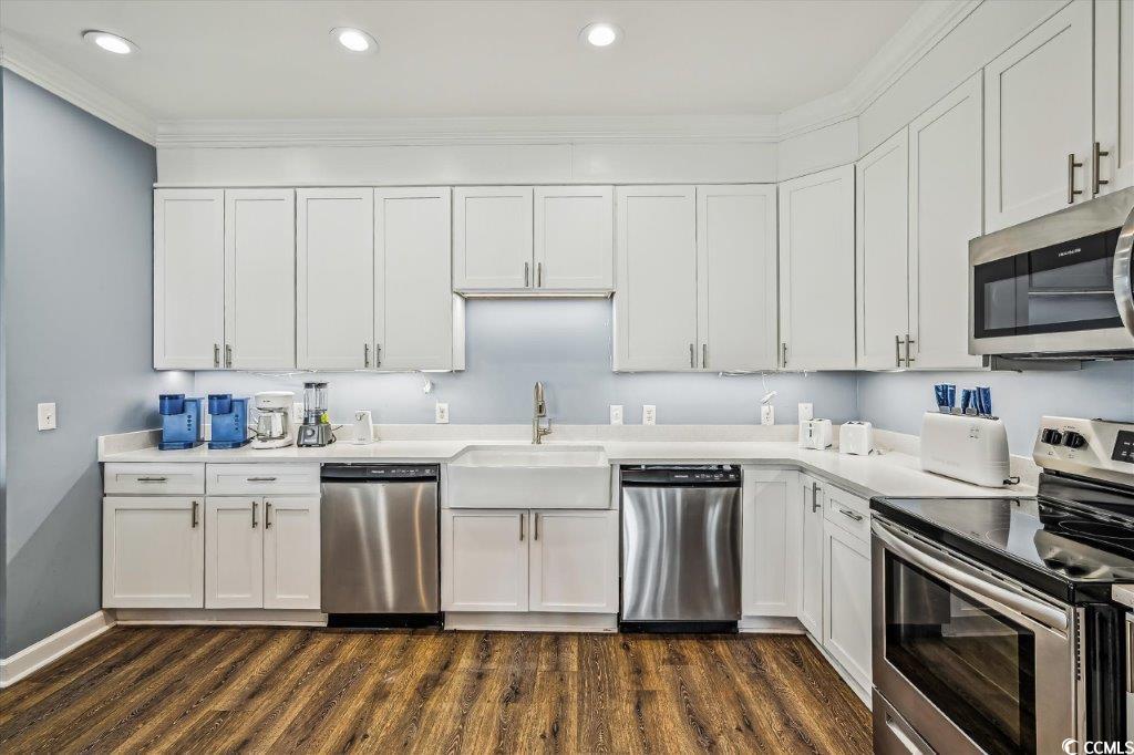 931 South Ocean Boulevard North Myrtle Beach, SC 29582 - Photo 11 of 40 Kitchen featuring appliances with stainless steel finishes, white cabinetry, dark wood-style flooring, ornamental molding, and recessed lighting