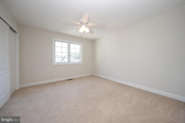 an empty room with windows and chandelier fan
