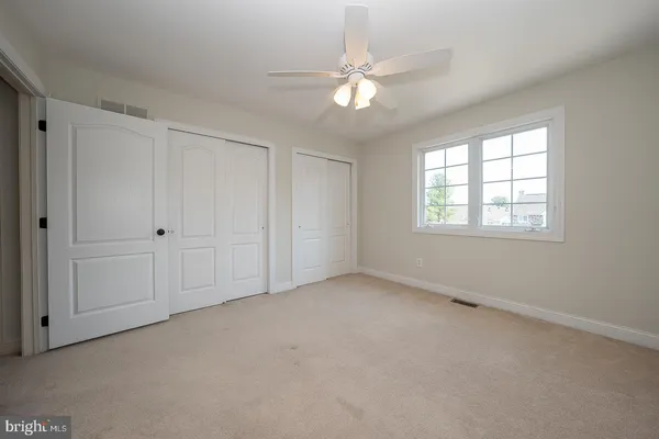 an empty room with chandelier fan and windows
