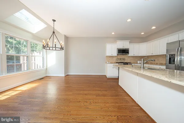 a kitchen with stainless steel appliances granite countertop a sink a stove and a wooden floors