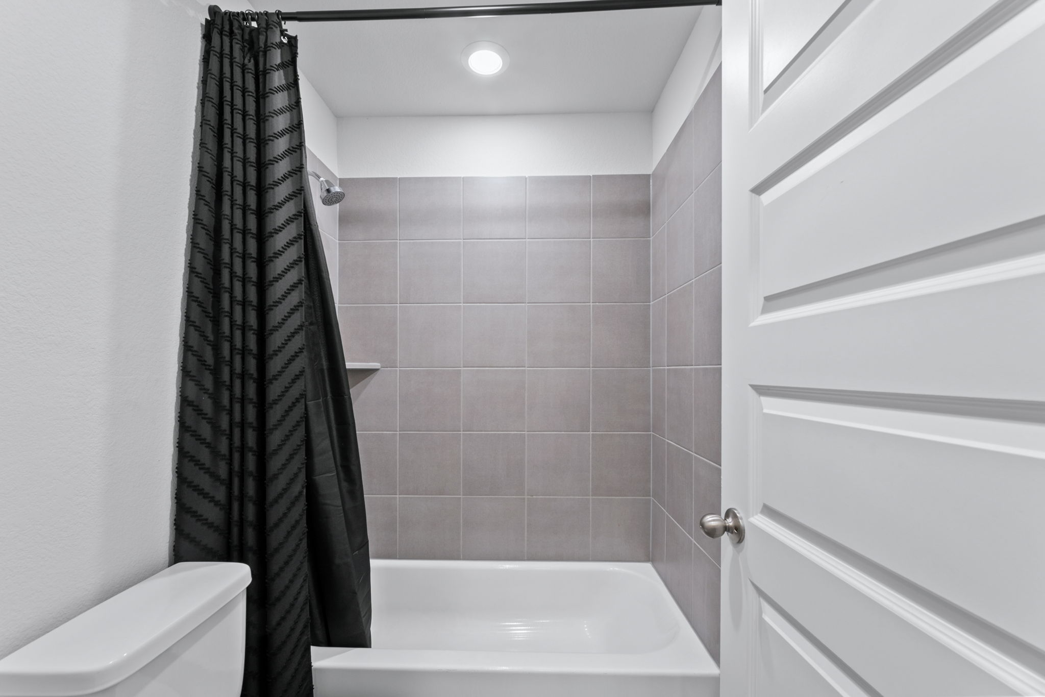 7312 Travertine Spring Drive Austin, TX 78744 - Photo 25 of 32 A well-appointed bathroom with tile shower walls and recessed lighting awaits relaxation.