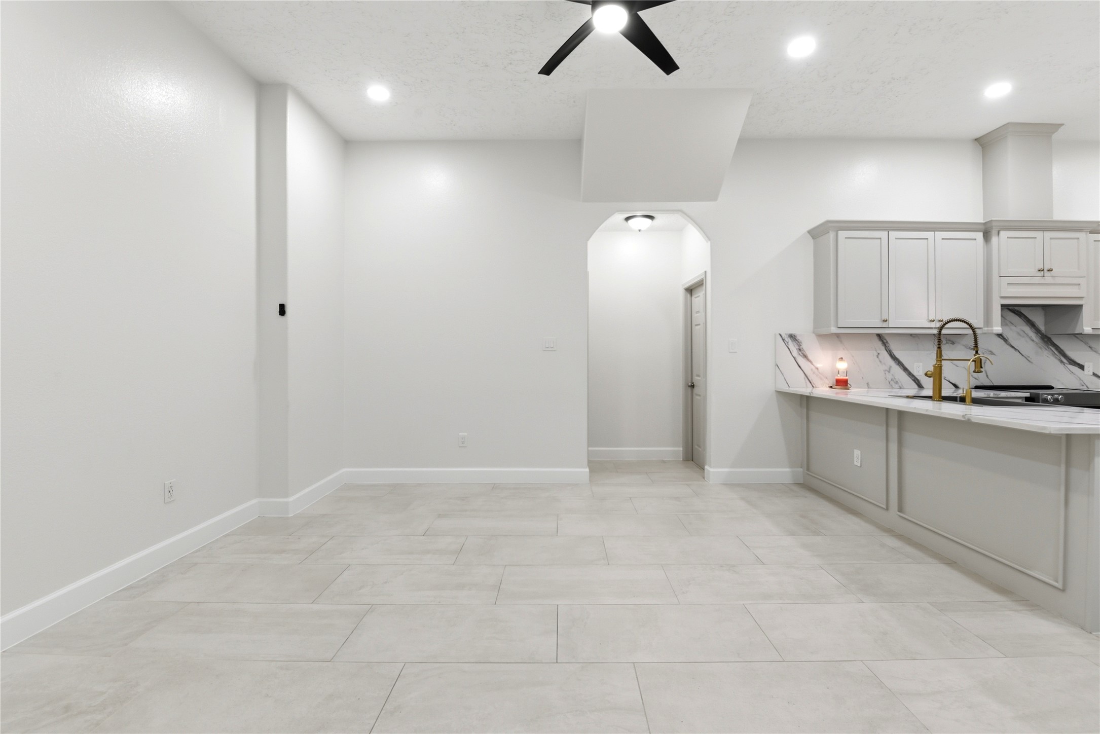 9403 Spaulding Street Houston, TX 77016 - Photo 14 of 50 Bright and modern kitchen with tile flooring, recessed lighting, and a ceiling fan. Features a spacious layout with a marble backsplash and a sleek countertop, ideal for cooking and entertaining.