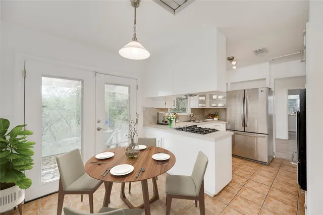 a kitchen with stainless steel appliances granite countertop a dining table chairs and refrigerator